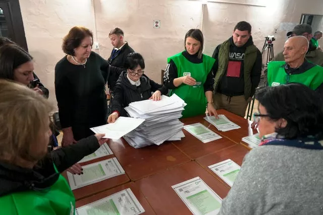 Ballots counted at table with people in green vests