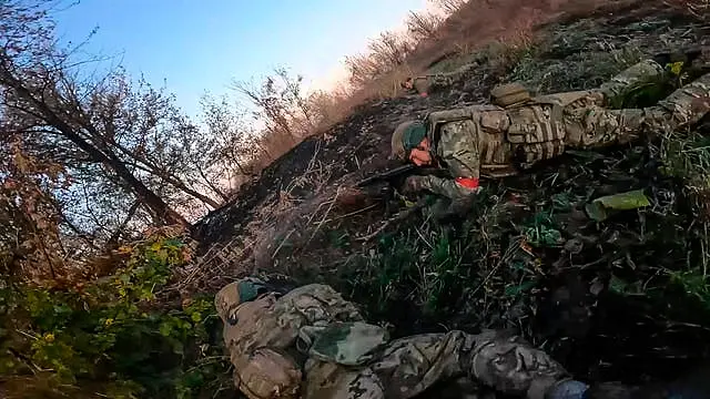 Russian soldier looks through sight on gun while lying on ground