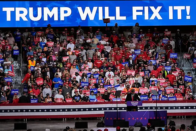 Donald Trump speaks before a 'Trump Will Fix It' banner