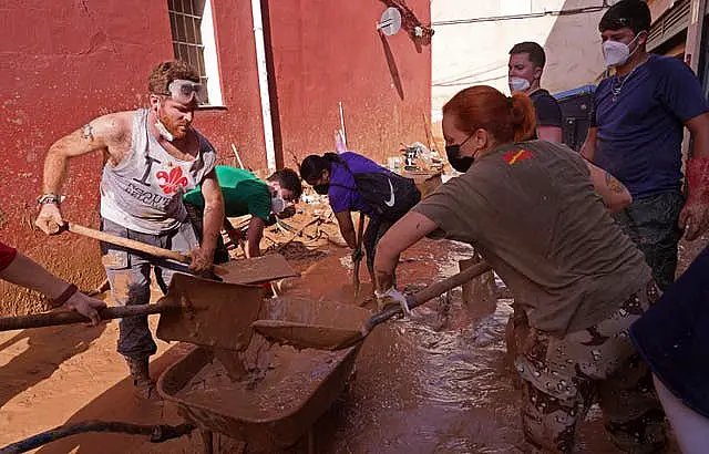 People shovel away mud after floods in Catarroja, Spain