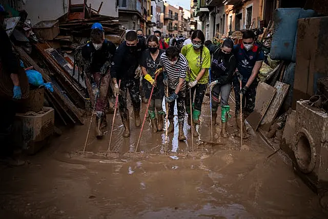 Volunteers and residents clean the mud from the streets in an area affected by floods in Paiporta, Valencia, Spain