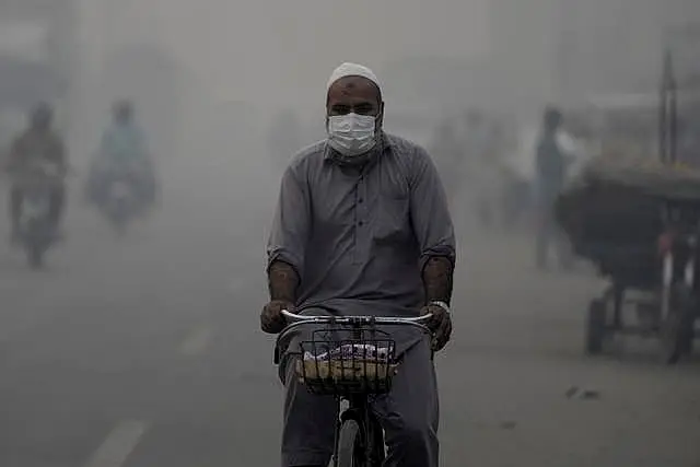 A cyclist, wearing a mask, heads to work amid the smog in Lahore