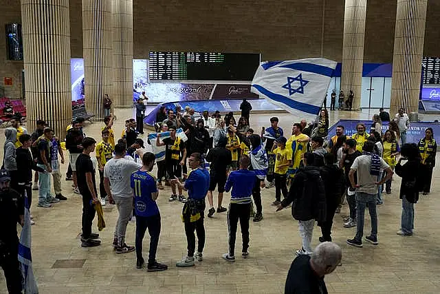 People welcome Maccabi Tel Aviv soccer fans as they arrive at Israel’s Ben-Gurion International Airport