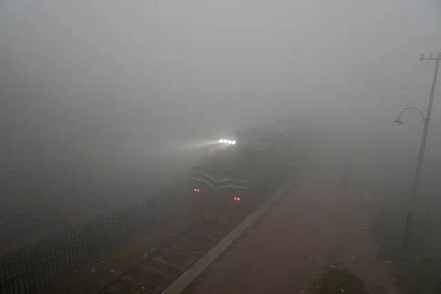 A commuter train's headlights can just be seen as smog envelops an area of Lahore, Pakistan 