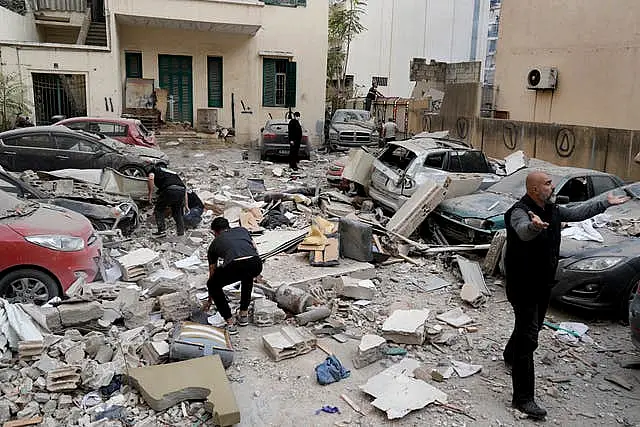 People search through the rubble of a destroyed building at the site of an Israeli air strike in central Beirut