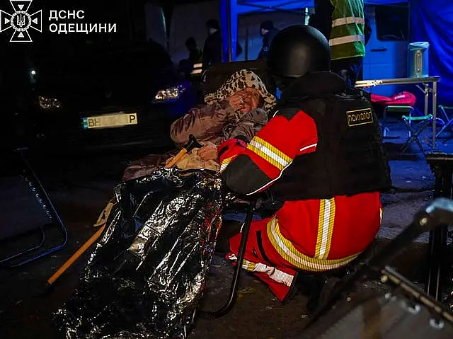 An emergency services worker calms down an elderly resident after Russian missile hit her home