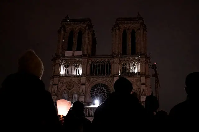 People watch Notre-Dame cathedral after a procession to bring the Virgin Mary statue from Saint-Germain l’Auxerrois church to the cathedral in Paris