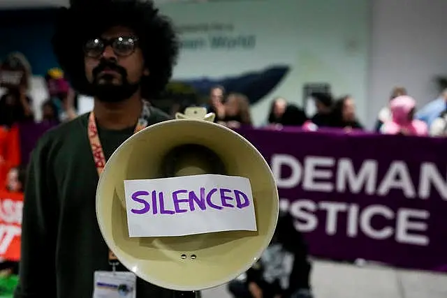 An activist holds a megaphone that says silenced