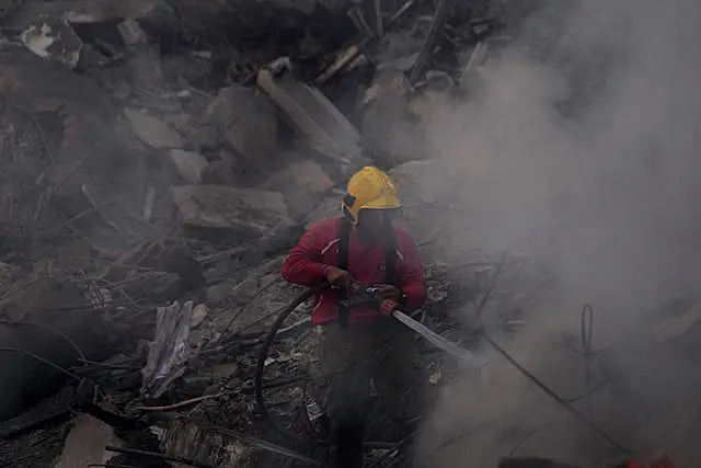 Firefighter uses water hose amid rubble