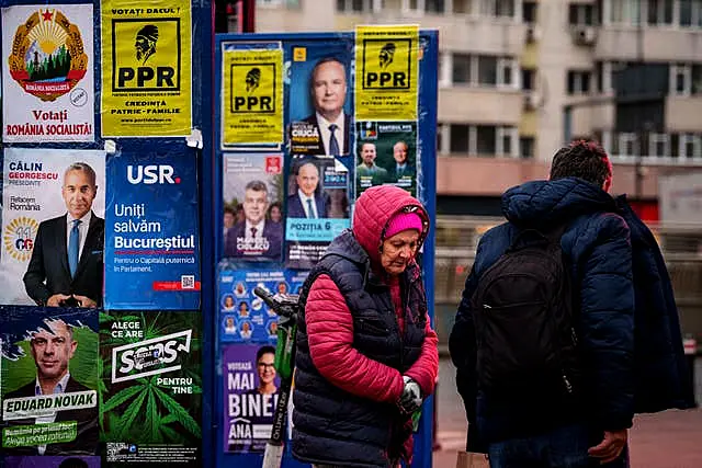 People walk past panels displaying electoral posters ahead of the presidential elections in Bucharest, Romania 