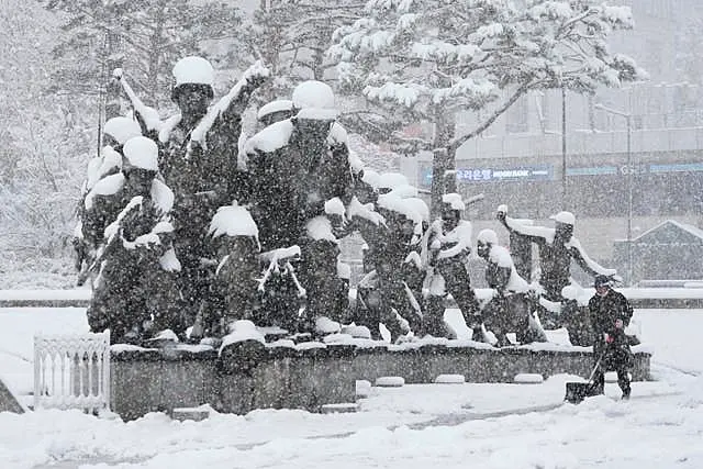 A worker shovels snow near a monument in remembrance at the Korea War Memorial Museum in Seoul