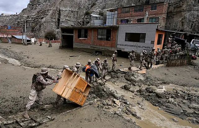 Soldiers recover a piece of furniture from a home flooded by a landslide caused by heavy rains in La Paz, Bolivia