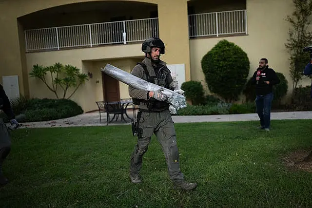 An Israeli bomb squad policeman carries the remains of a rocket that was fired from Lebanon in Kibbutz Kfar Blum, northern Israel 