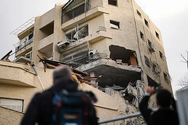 Journalists take pictures of a building hit direct by a rocket fired from Lebanon in Haifa, Israel