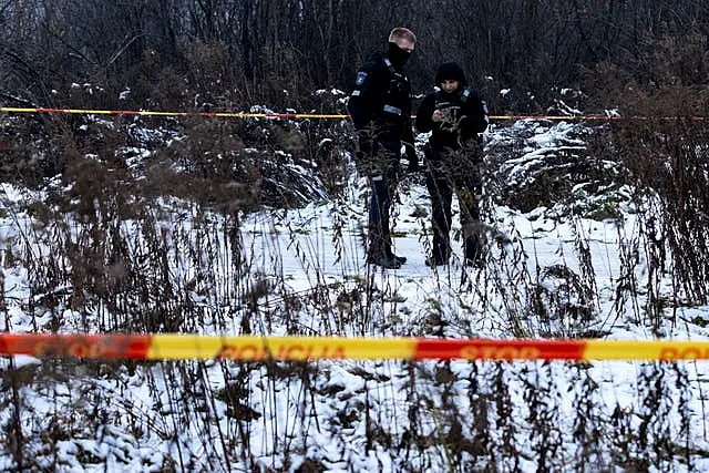 Crash investigators in a forest behind a taped-off area