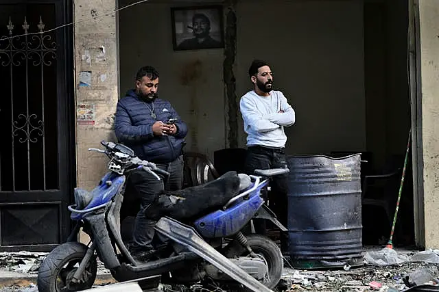 Lebanese men stand outside their damaged shop,