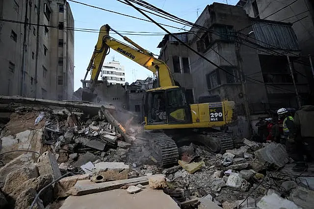 Rescuers use an excavator as they search for victims at the site of an Israeli air strike in Beirut, Lebanon