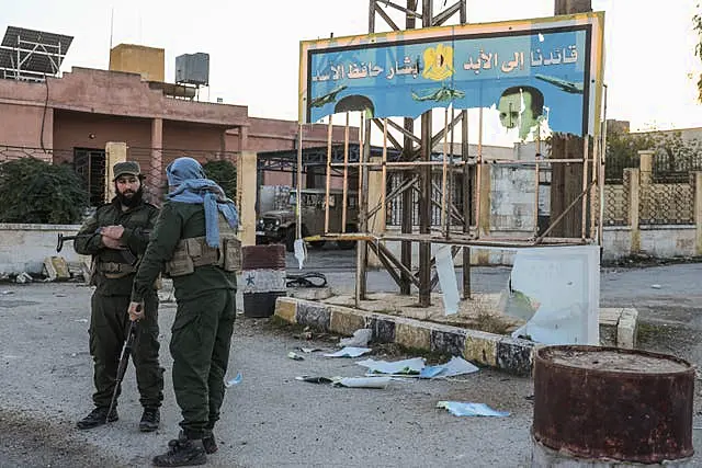 Syrian opposition fighters stand next to a government sign after entering the village of Anjara