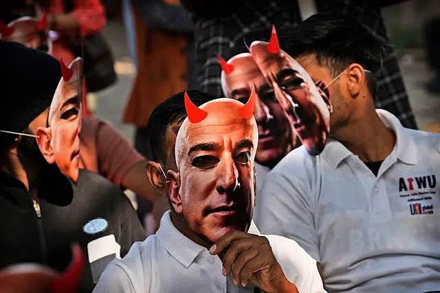 People wear masks of Amazon’s Jeff Bezos during a protest in New Delhi, India