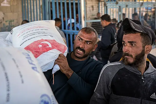 A man grabs a sack of donated flour at a UNRWA distribution center in the Nuseirat refugee camp