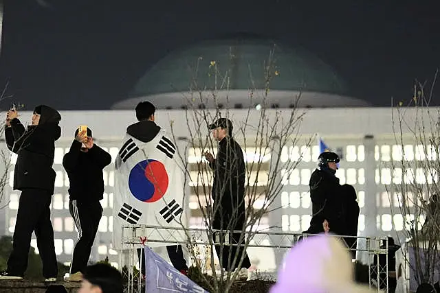 A man wearing a national flag stands on the wall of the National Assembly in Seoul, South Korea