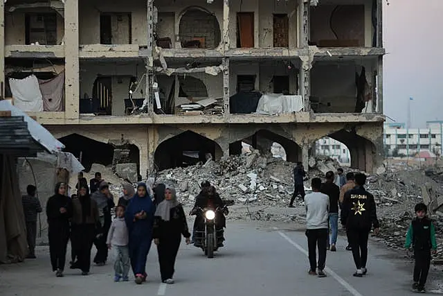 People walk in front of a wrecked building