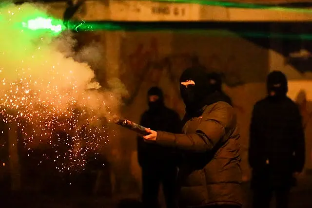 A demonstrator launches a firecracker towards police