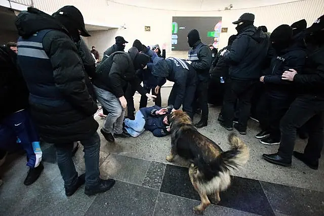 Police officers detain a demonstrator at a subway station