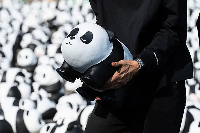 A staff member carries one of the 2500 panda sculptures displayed at the Hong Kong International Airport 