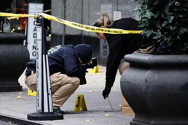 Detectives kneel to examine evidence on pavement