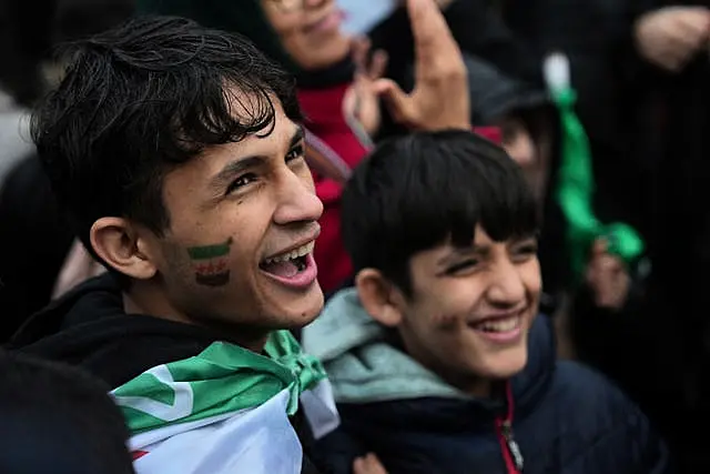 Young boys draped in Syrian flags smile