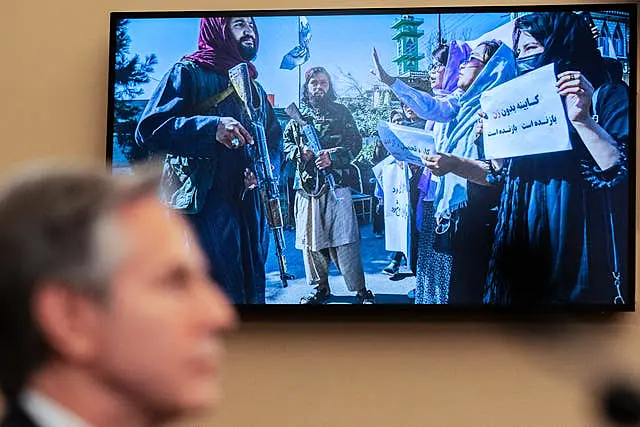 Antony Blinken speaks as a photograph from Afghanistan is seen on a television screen