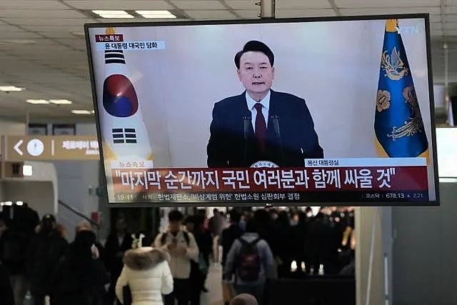 A TV screen shows South Korean President Yoon Suk Yeol’s televised briefing at a bus terminal in Seoul