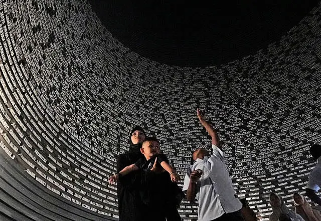 Visitors looks at a wall displaying the names of the victims of 2004 Indian Ocean tsunami, at the Tsunami Museum in Banda Aceh