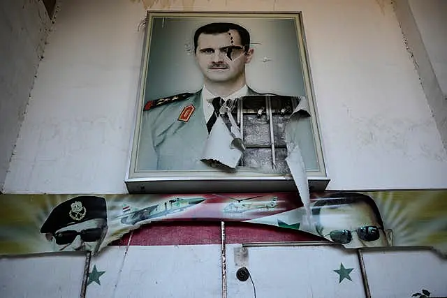 A torn posters shows the late Syrian President Hafez Assad and his son the ousted Syrian president Bashar Assad, that were set at the entrance of the notorious security detention centre called Palestine Branch, in Damascus, Syria