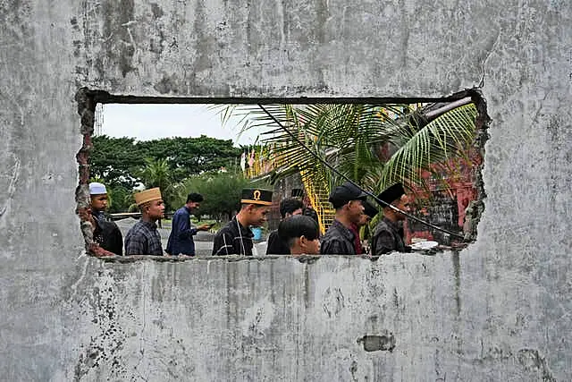 People are seen through a hole in the wall of a building damaged by the tsunami in Banda Aceh 