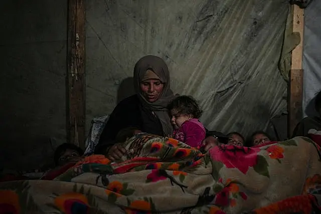 Woman and several small children under blanket