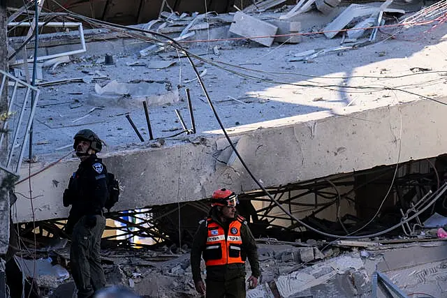 People examine the damage caused by a Houthi missile