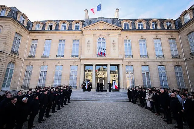 People stand in silent tribute at the Elysee Palace