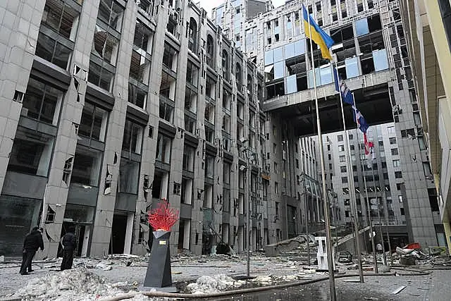 People stand next to buildings destroyed by the recent Russian attacks in Kyiv,