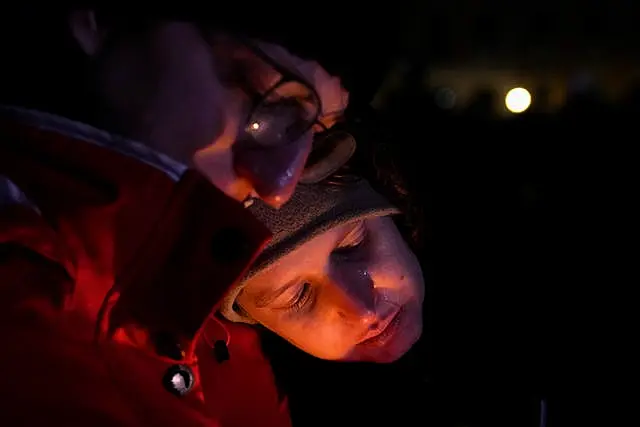 A mourner rests his head on another person's shoulder in front of Magdeburg Cathedral during a memorial service for those killed