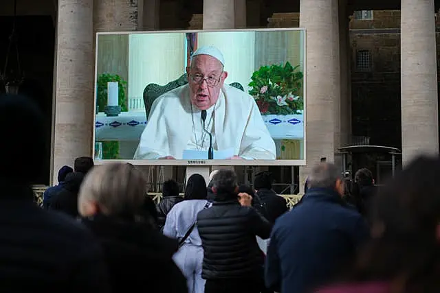 Pope Francis on big screen in front of crowd of people