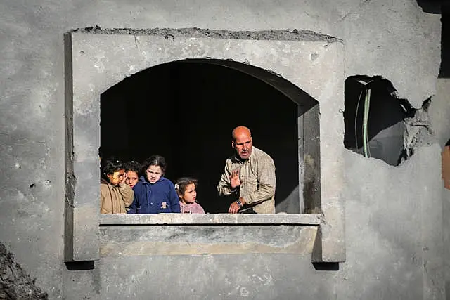 Neighbours watch the funeral procession of the victims of an Israeli air strike on a home in Deir al-Balah, central Gaza Strip