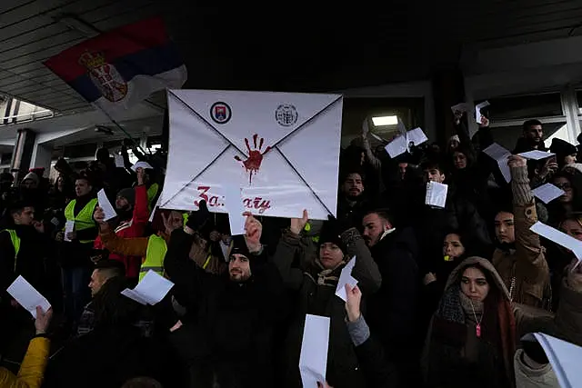 Students shouting slogans and holding a banner with a red handprint on it during a protest