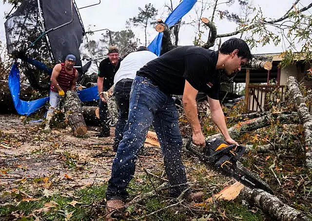 Ricardo Rodriguez uses a chain saw to remove debris from a woman’s home