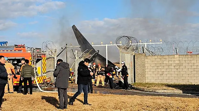 Firefighters and rescue team members work at the Muan International Airport