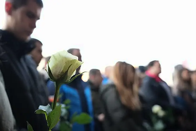 Students hold white flowers in front of the court building