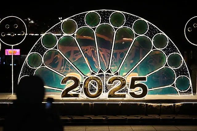 A woman holds her smartphone near an illuminated decoration on New Year’s Eve in Seoul, South Korea