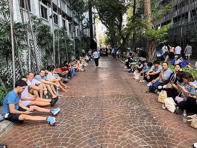 People sitting outside the Sathorn Gardens condominium building in Bangkok