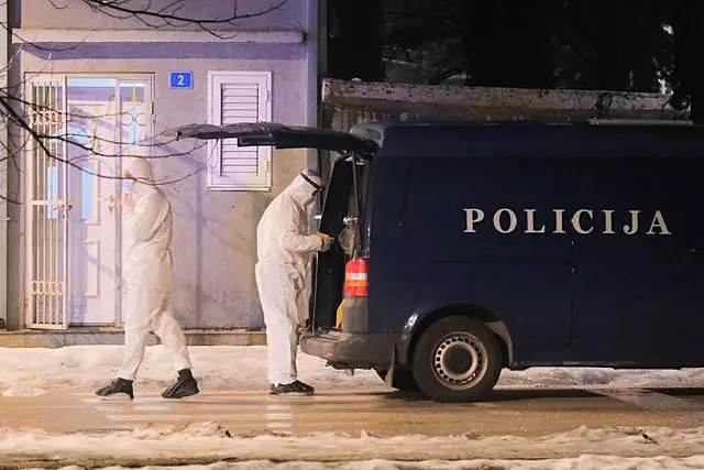 Police investigators in forensic suits beside a police van at the scene of the shooting